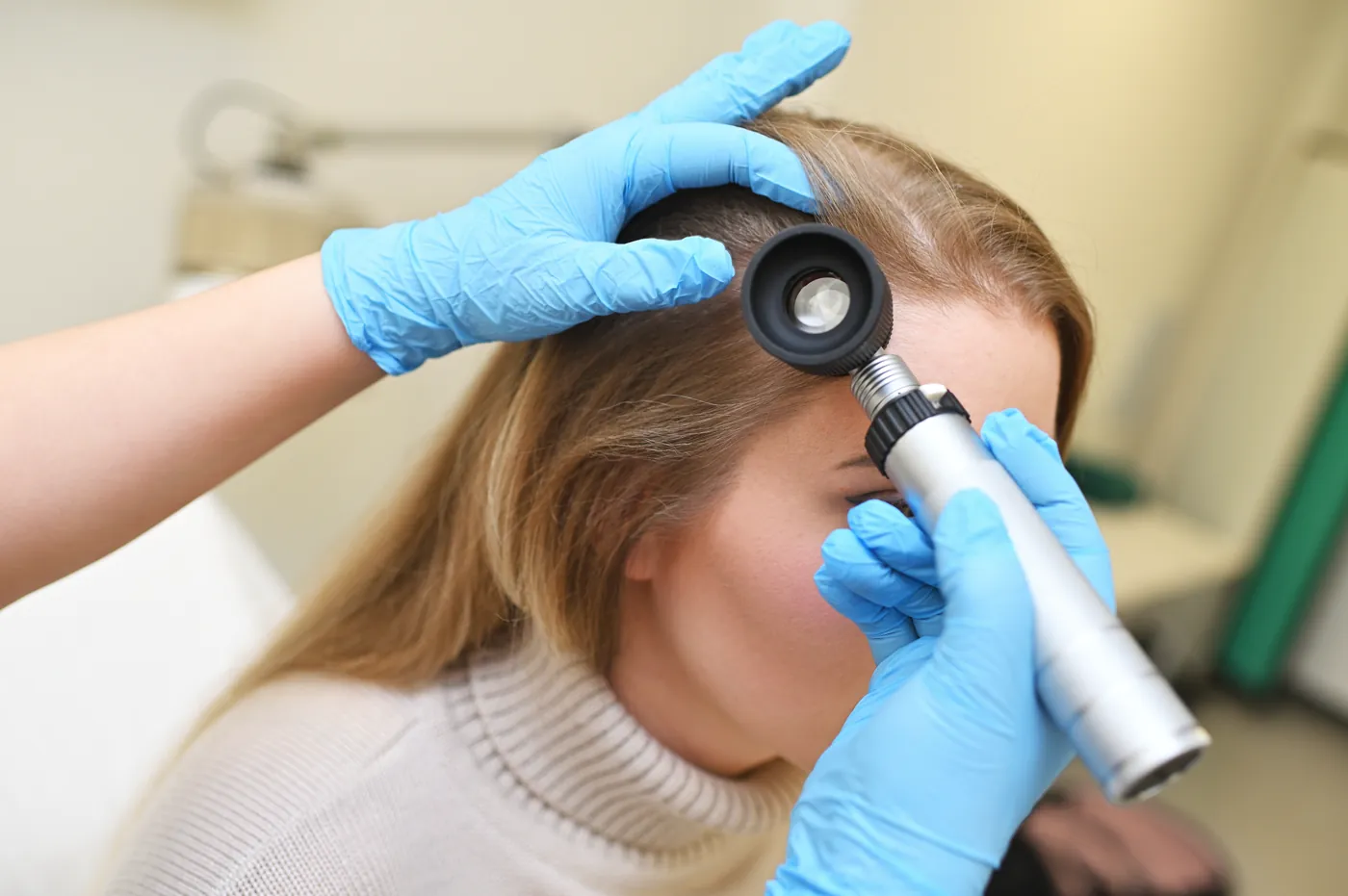 Especialista examinando el cuero cabelludo con un dermatoscopio