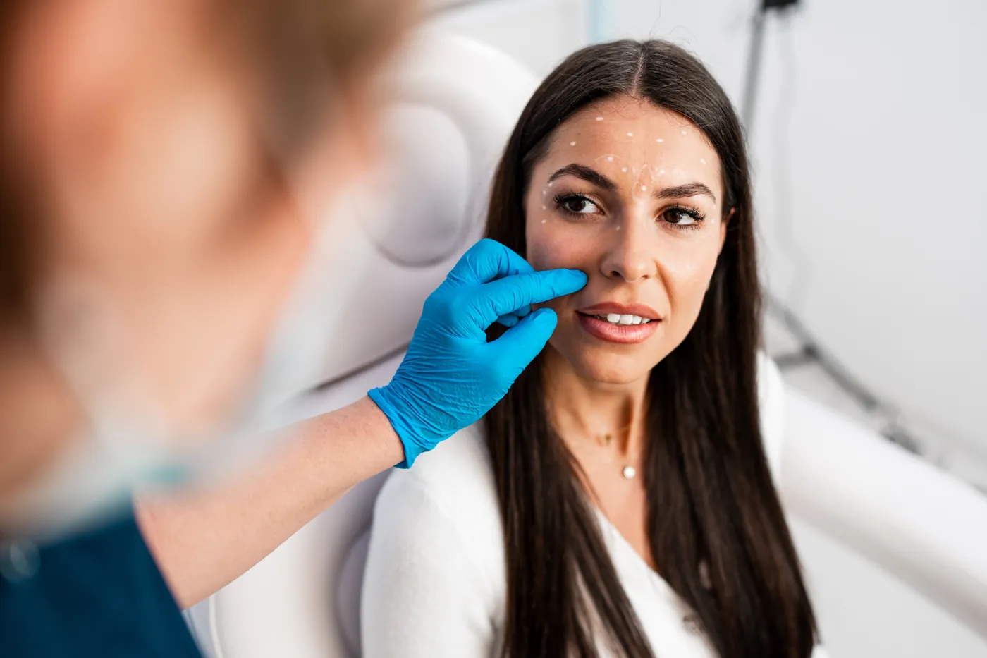 Aesthetic medicine professional assessing a patient's face