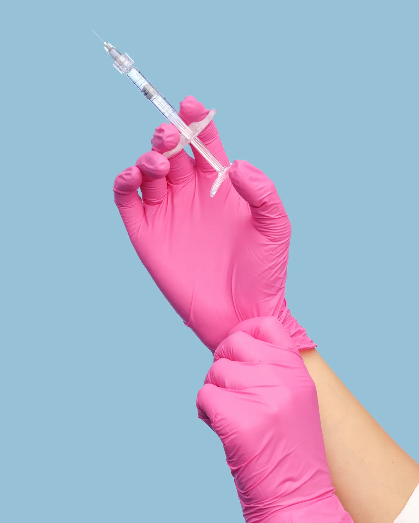Manos con guantes sosteniendo una jeringa para un procedimiento estético